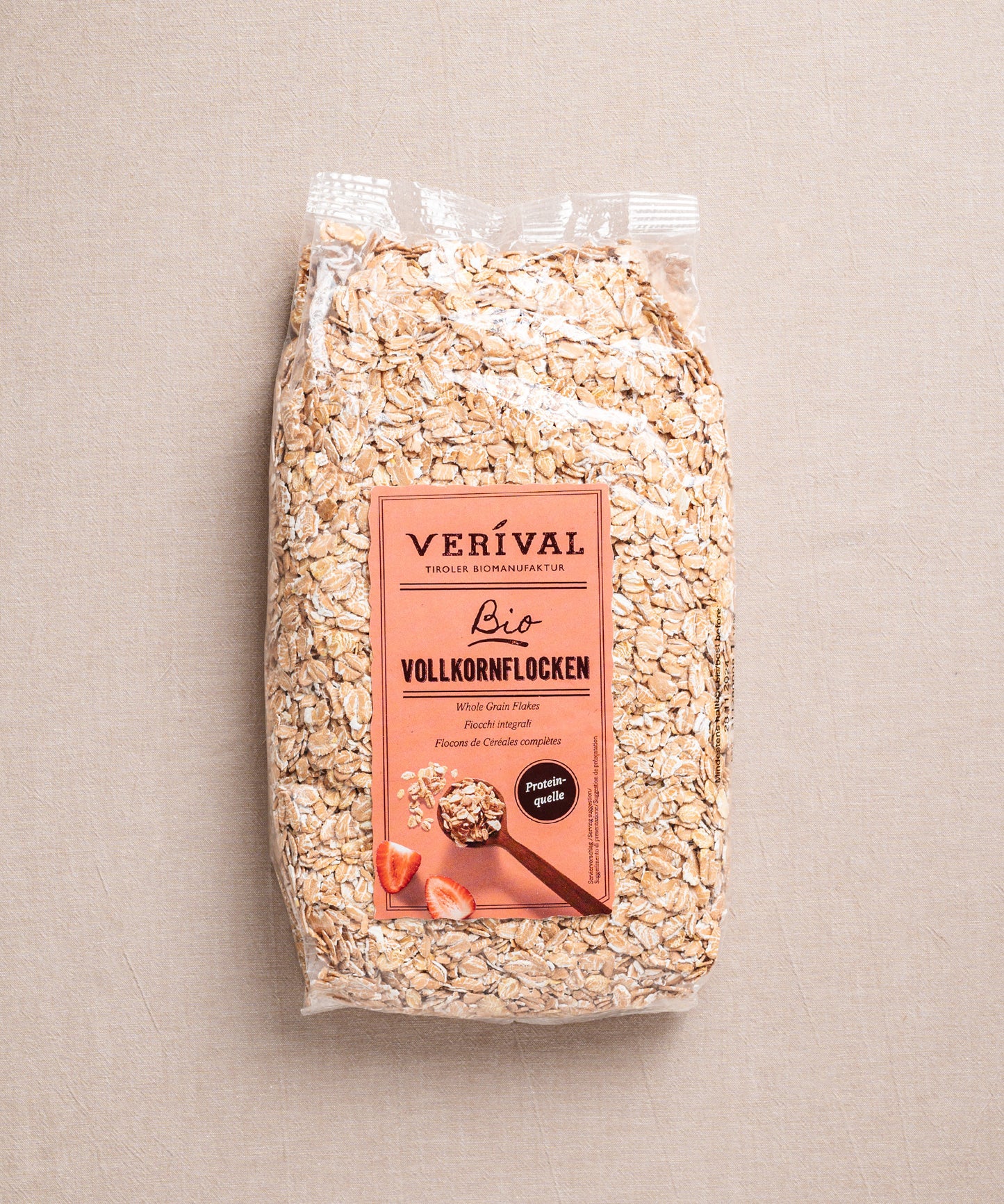 Klarsicht-Beutel mit Vollkornflocken von Verival Bio, reich an Ballaststoffen und pflanzlichen Proteinen, mit Erdbeeren und einer Schale Müsli auf dem Etikett.