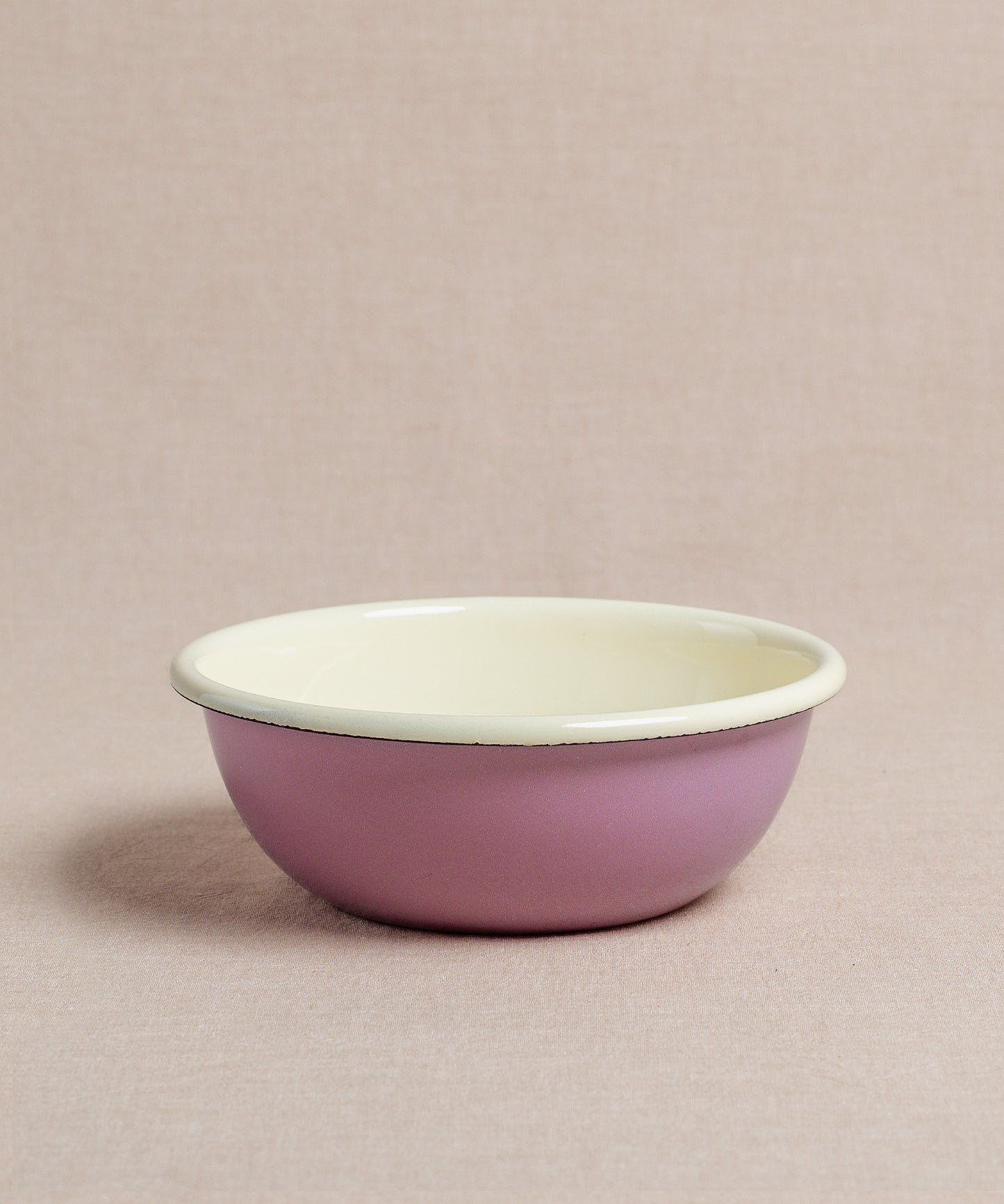 Eine runde, flache Riess Emaille-Schüssel mit rosafarbener Außenseite und cremefarbener Innenseite, perfekt für Ihren Porridge, auf einem neutralen Hintergrund platziert.